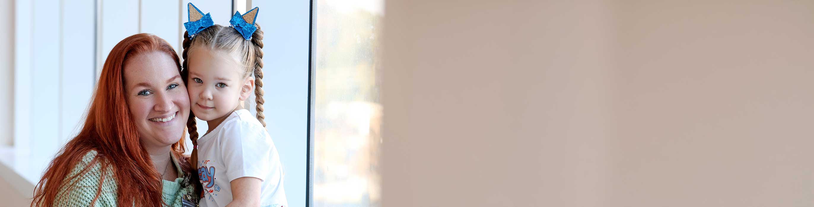 A smiling woman holding her young daughter.