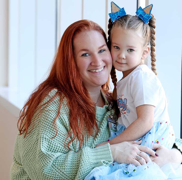 A smiling woman holding her young daughter.
