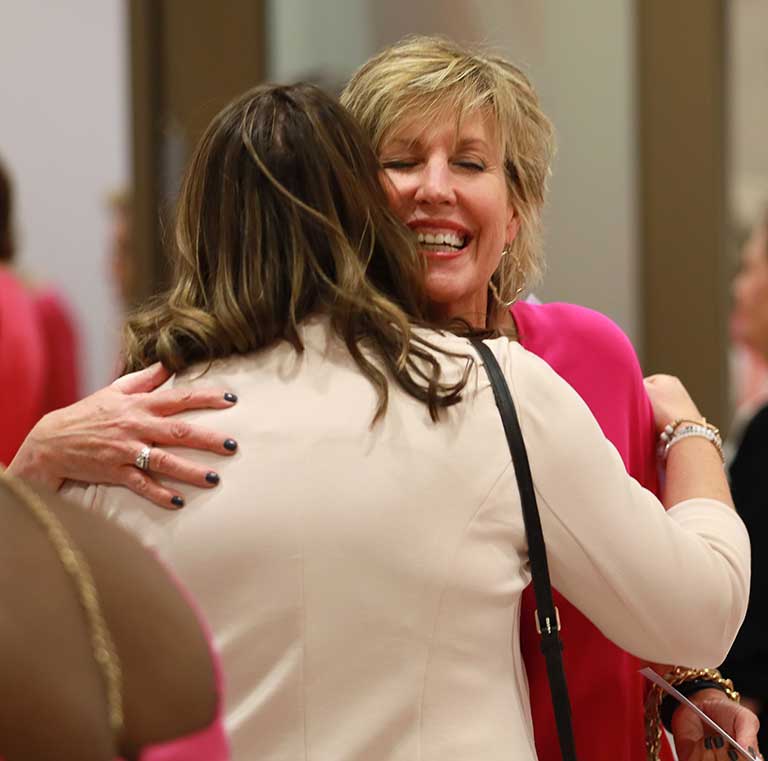 Two women smiling and hugging.