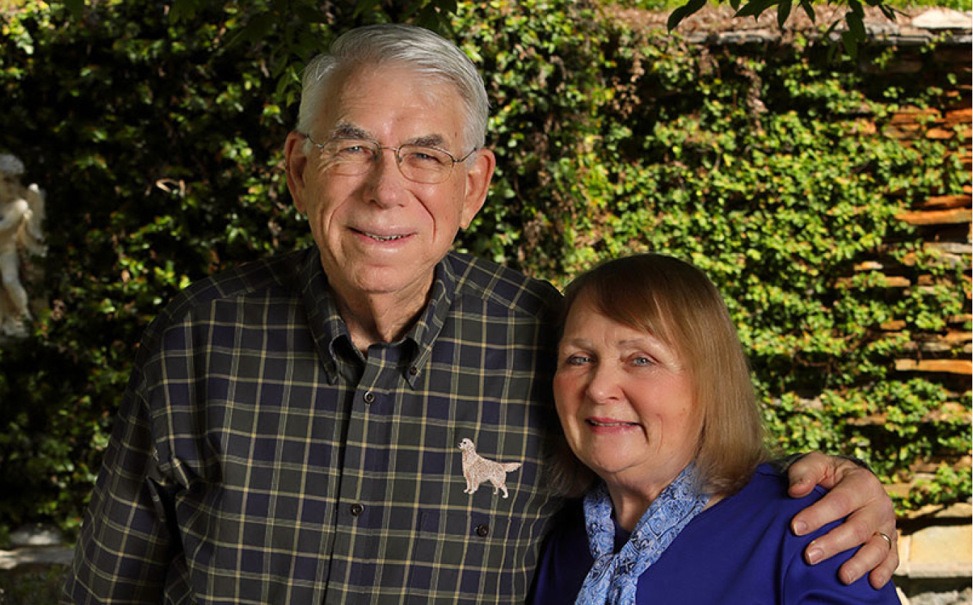 A couple that has donated to the Foundation posed in front of a holly hedge.