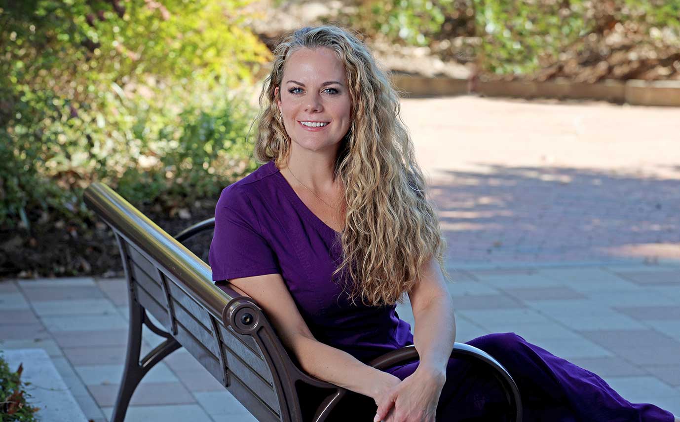 A smiling woman sitting on a bench.